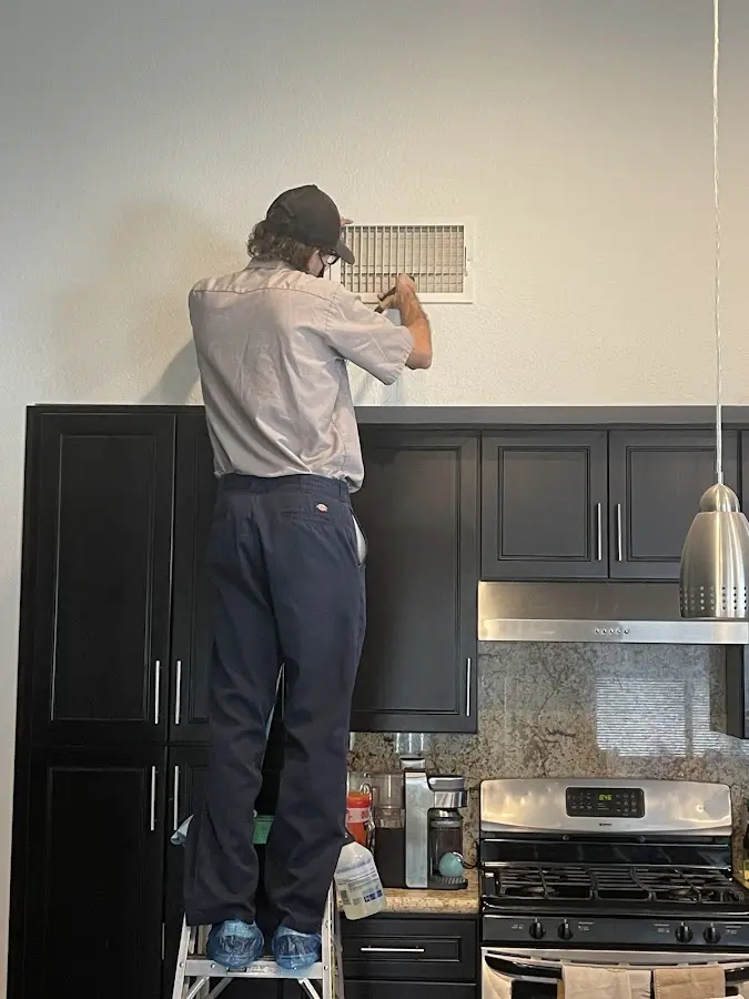 Technician inspecting an air vent during HVAC service in Kirksville